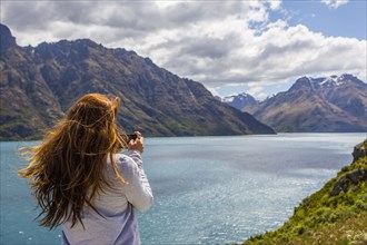 Caucasian woman photographing mountains and lake