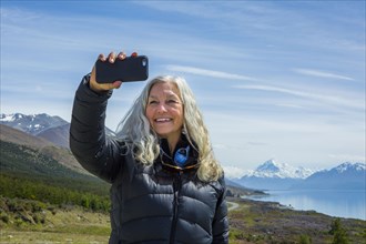Caucasian woman photographing remote landscape