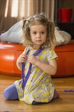 Caucasian preschooler girl playing dress-up with necklace