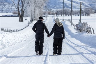 Caucasian couple walking on snowy remote road