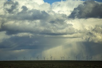 Storm clouds over wind turbines in rural landscape