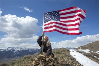 Caucasian woman planting American flag on remote hilltop