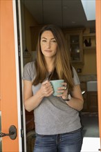 Woman standing in doorway drinking coffee