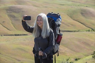 Older Caucasian woman hiking with backpack taking selfie