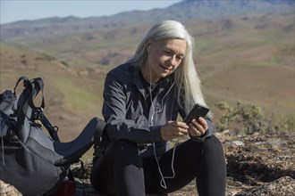 Older Caucasian woman listening to cell phone on mountain