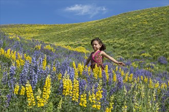 Caucasian girl standing on hillside with wildflowers