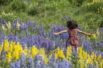 Caucasian girl running on hillside with wildflowers
