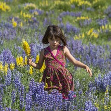 Caucasian girl holding bouquet on hillside with wildflowers