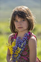 Serious Caucasian girl holding bouquet wildflowers