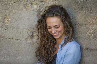 Laughing Caucasian woman leaning on concrete wall