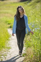 Caucasian woman walking on path near tall grass