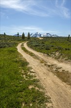 Winding dirt road near snow covered mountain range