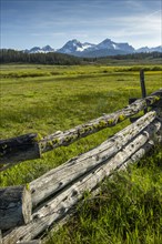 Wooden log fence in field near mountain range