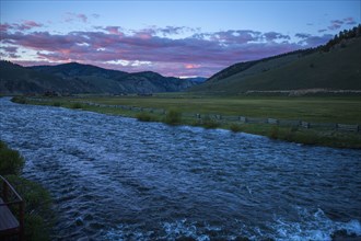 River near rolling landscape at sunset