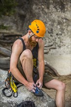 Caucasian rock climber tying shoe