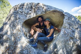 Caucasian couple sitting in rock formation