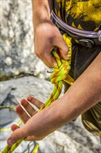 Caucasian rock climber fastening rope to harness