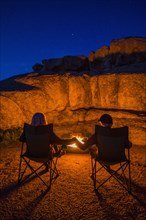 Caucasian couple holding hands near campfire at night