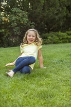 Smiling Caucasian girl sitting in grass