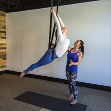 Instructor assisting student hanging from silks