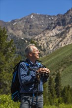 Caucasian man hiking in mountains with binoculars