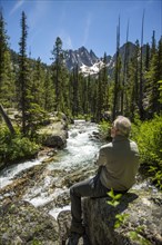 Caucasian man sitting on rock at mountain river