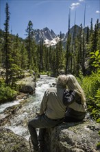 Caucasian couple hugging on rock at mountain river