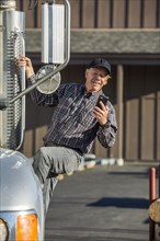 Caucasian man climbing into semi-truck texting on cell phone