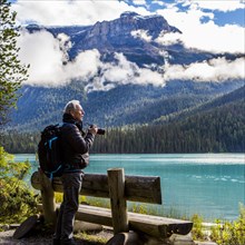 Caucasian man photographing mountain lake