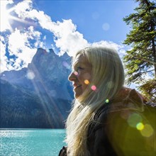 Sunbeams on face of Caucasian woman at mountain lake
