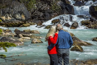 Caucasian couple admiring rapids over rocks
