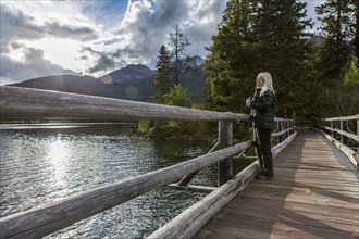 Caucasian woman holding binoculars at mountain lake