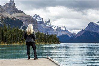 Caucasian woman standing at the end of dock on mountain lake