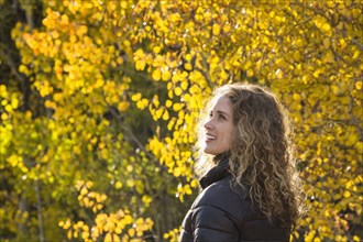 Smiling Caucasian woman under autumn leaves
