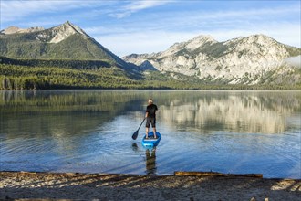 Caucasian man paddleboarding on mountain lake