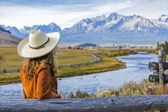 Caucasian woman leaning on wooden fence near mountain river
