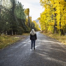 Caucasian woman standing in road near trees