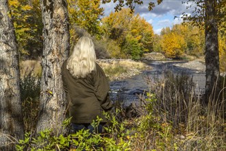 Caucasian woman leaning on tree near river