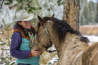 Caucasian woman petting horse in winter