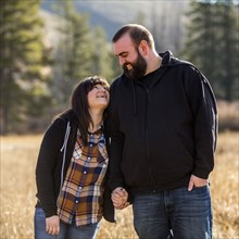 Smiling Caucasian couple holding hands in field