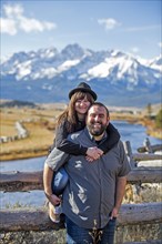 Smiling Caucasian couple posing at wooden fence near river