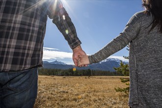 Caucasian couple holding hands in field
