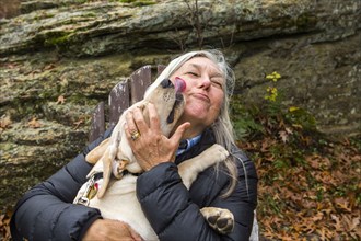 Dog licking face of Caucasian woman outdoors