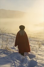 Caucasian woman standing in winter landscape at sunset