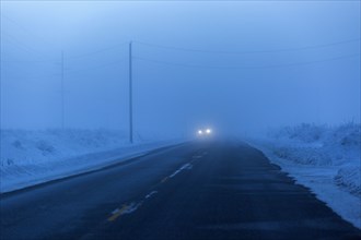 Approaching headlights from car driving in winter