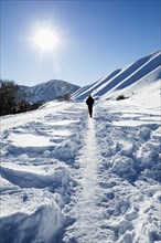 Caucasian man hiking on trail in snow on sunny mountain