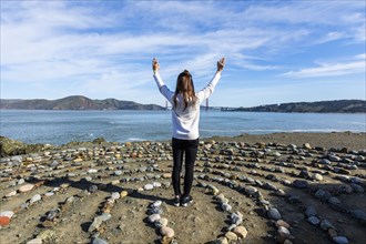 Caucasian woman standing in circle of rocks near ocean