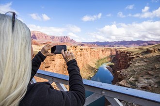 Caucasian woman photographing canyon river with cell phone