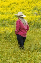 Caucasian woman walking in field of yellow flowers