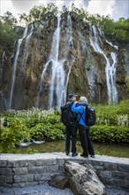 Older Caucasian couple hugging near waterfall